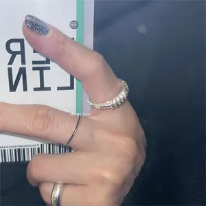 Close-up of a silver twisted rope ring and simple minimalist bands worn on fingers