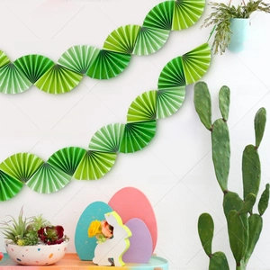 Detail of green paper fan banner hung on a white wall for festive party decoration