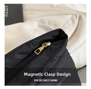 Detail of black quilted shoulder bag featuring gold zipper and magnetic snap closure