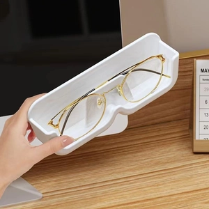 Wall-mounted white plastic glasses storage box with gold round spectacles on desk