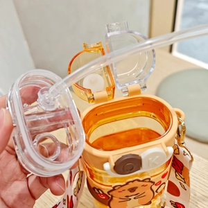 Detail of orange cartoon bear water bottle with straw and adjustable carry strap
