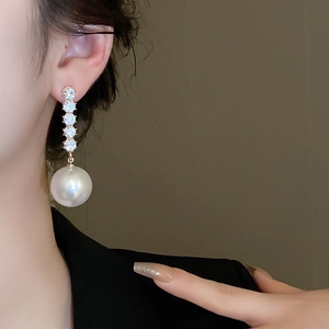 Detail shot of elegant long earrings with vertical diamonds and a large white pearl