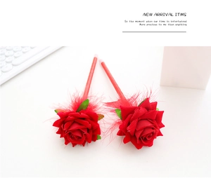 Detail of red rose pens featuring soft velvet petals and delicate feather accents
