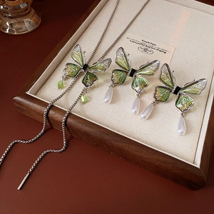 Detail of butterfly necklace and earrings with green enamel and pearl droplets