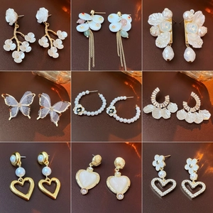 Collection of nine elegant gold-plated floral and butterfly earrings on leather background