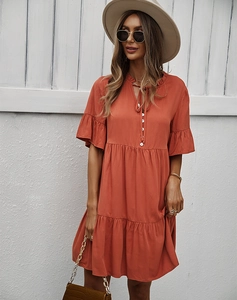Détail d'une robe orange à manches volantées, patte de boutonnage et jupe à volants