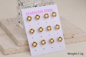 Macro view of six pairs of vintage gold flower and pearl stud earrings on white stone