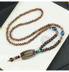 Close-up of ethnic wooden bead long necklace with striped agate pendant and colorful tassel