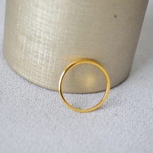 Close-up of a minimalist gold-plated wave curve brass ring with a polished glossy finish