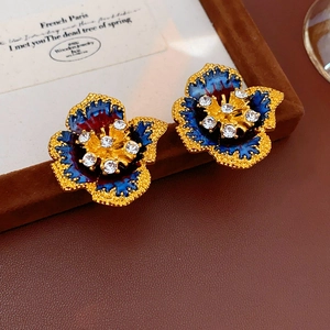 Close-up of vintage flower earrings with blue enamel and crystals on brown velvet