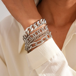 Detail of four-piece silver metal chain bracelets layered on a female model's wrist