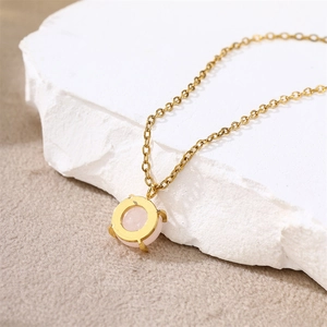 Detail of 18k gold necklace featuring a rose quartz pendant on a textured rock surface