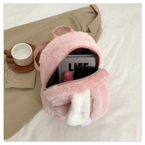 Flat lay of pink plush bunny ear backpack with fuzzy texture and zipper on fabric background