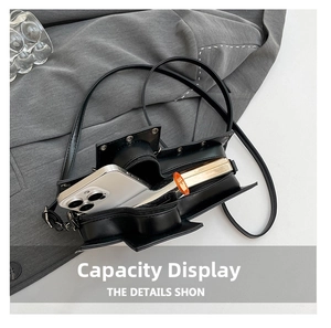 Detail showing internal capacity of gothic rivet crossbody bag with phone and lipstick