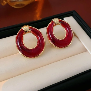 Detail view of red translucent resin earrings with gold edges on jewelry cushion