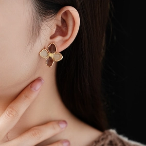 Close-up of vintage flower earrings with gold frame and brown resin on model ear