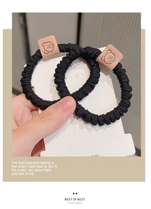 Detail of two black elastic scrunchies with cute bear leather patch on card display