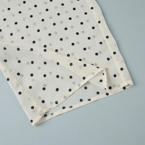 Close-up of polka dot fabric edge with neat hem stitching on summer two-piece outfit