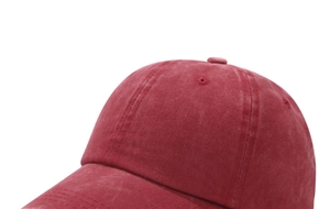 Detailed close-up of burgundy washed cotton baseball cap texture and stitching