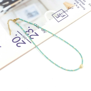 Detailed macro of mint green crystal beads and gold heart pendant on a thin necklace