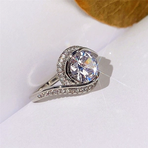 Vista macro de anillo de bodas plateado con una gran circonita en engaste de remolino