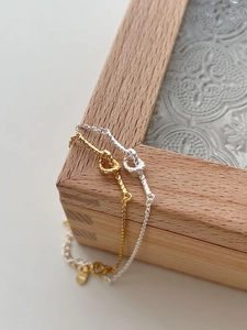 Detailed view of woven knot bracelets in gold and silver finish on a decorative wooden box
