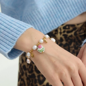 Elegant gold pearl bracelet featuring a hand-painted tulip ceramic heart charm on wrist