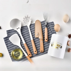 Close-up of white silicone kitchen tools with wooden handles in a storage bucket