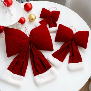 Three red velvet Christmas bows with white faux fur trim on a white tabletop