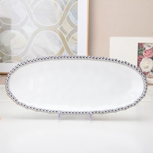 Macro detail of a white oval ceramic dessert plate with fine silver beaded edge decoration