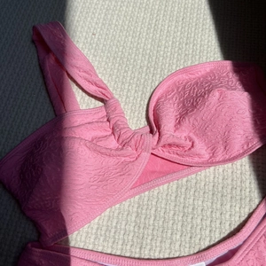 Detailed view of pink one-shoulder bikini top with embossed wavy texture fabric