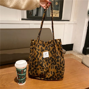Detalle del bolso tote de pana con estampado de leopardo, botón a presión y etiqueta blanca