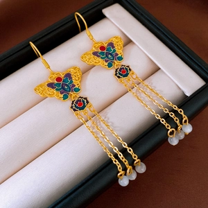 Close-up of golden enamel butterfly earrings with hanging tassels and white beads