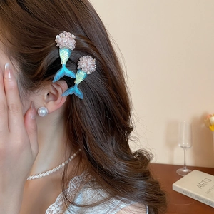 Detail view of a model wearing two blue mermaid tail hair clips with pink bead accents