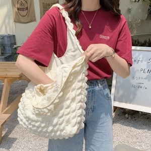 Detailed close-up of cream textured bubble tote bag showing large capacity in outdoor use