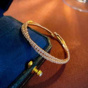 Macro detail of double-row pavé zircon open bangle with gold-plated finish on velvet box