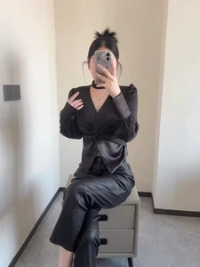 Dettaglio della camicia in raso nero con scollo a V, nodo in vita e trama liscia