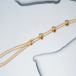 18k gold plated stainless steel bracelet featuring bezel-set diamonds on reflective surface