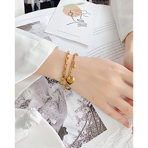 Detailed view of layered gold heart bracelet with rectangular links and polished beads