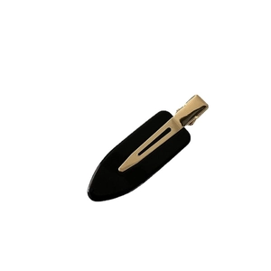 Sleek black acetate hair clip with golden metal base for styling and makeup hair fixing