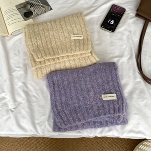 Soft wool blend knit scarves in beige and purple colors on white bedding surface
