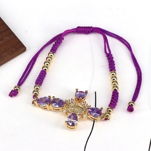 Macro view of purple cross charm bracelet with gold details and saint icon medal