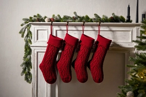 Set of four red cable knit Christmas stockings hanging on a white fireplace mantel decoration