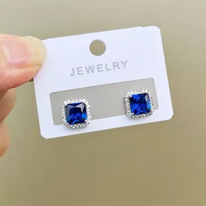 Detail view of square blue gemstone stud earrings with micro-set white rhinestones