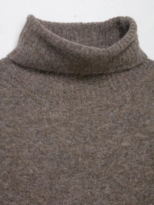 Detailed view of dark brown knitted dress featuring high turtleneck and wool blend texture
