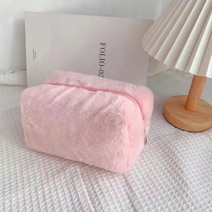 Close-up of pink plush makeup bag with fluffy texture and smooth zipper on a white desk