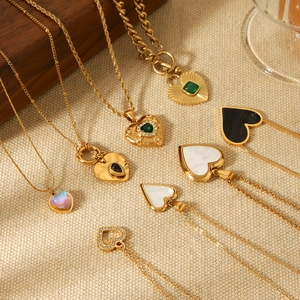 Golden heart pendant necklace set with colorful gems and pearls on beige fabric