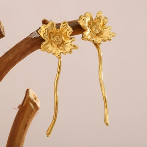 Vintage 18K gold plated stainless steel flower earrings hanging on a dry wooden branch