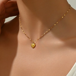 Close-up of a minimalist gold heart pendant necklace worn on a woman's neck