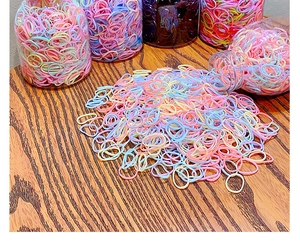 Colorful elastic hair bands in clear plastic jars on a rustic wooden tabletop
